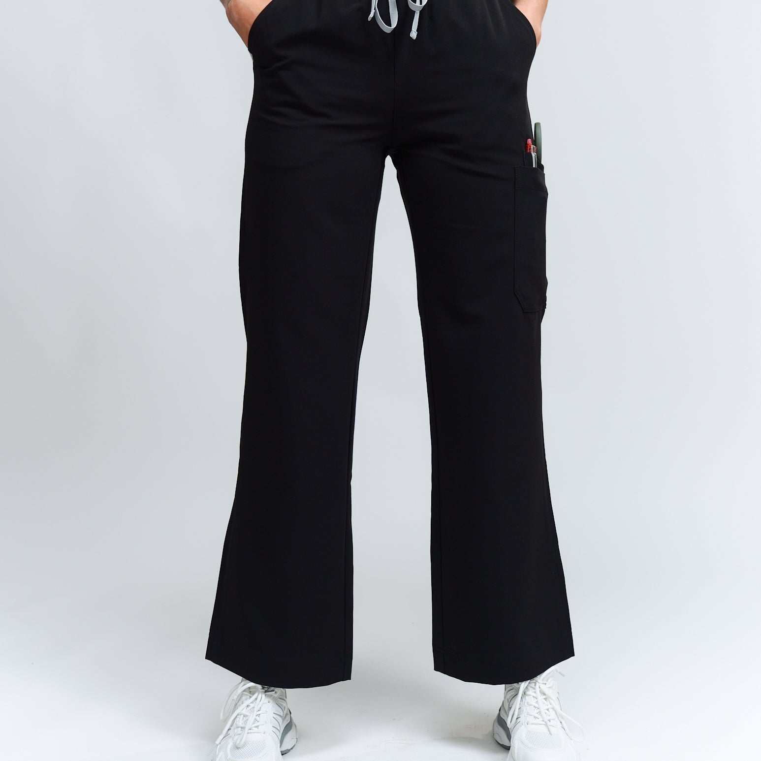 A person standing wearing high-waisted black wide leg scrub pants with an elastic waistband and antimicrobial fabric.