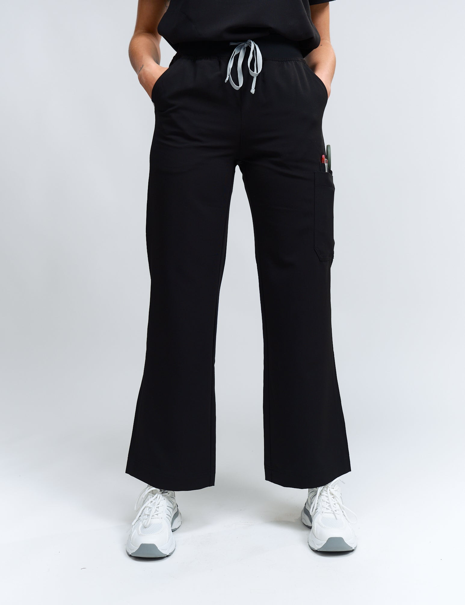 A person standing wearing high-waisted black wide leg scrub pants with an elastic waistband and antimicrobial fabric.